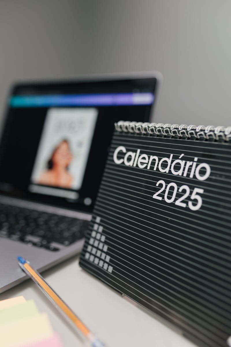 Close-up of 2025 desk calendar and laptop, ideal for office themes.