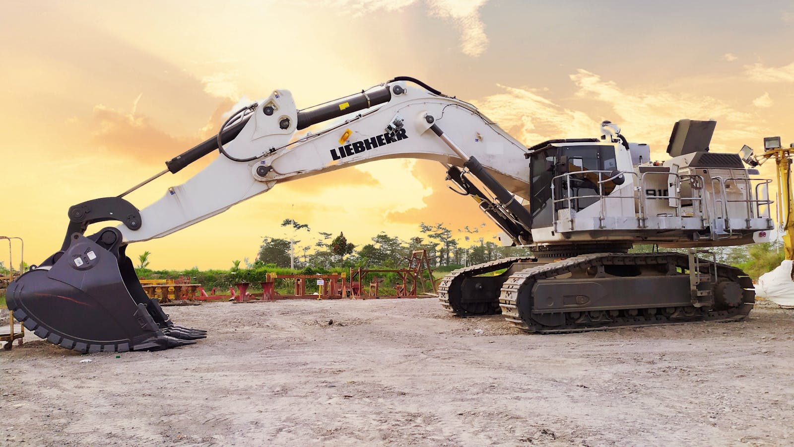 A large Liebherr excavator on a construction site in Kalimantan Selatan, Indonesia, at sunset.