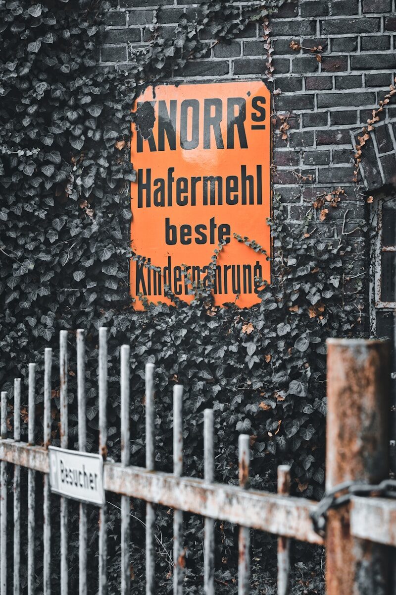Orange sign on brick wall covered in ivy