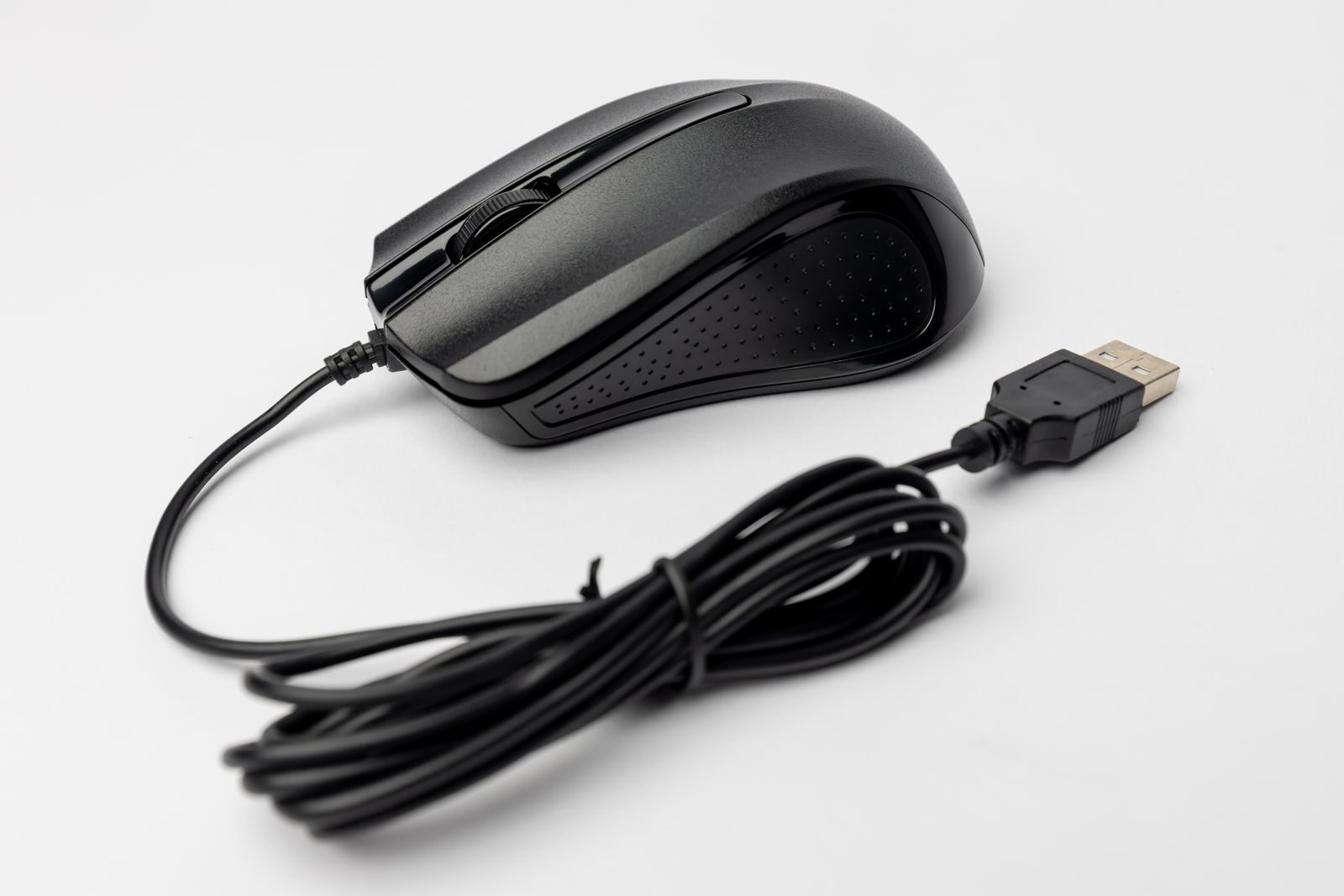 Close-up of a black wired computer mouse on a white background, showcasing its design and connection cable.