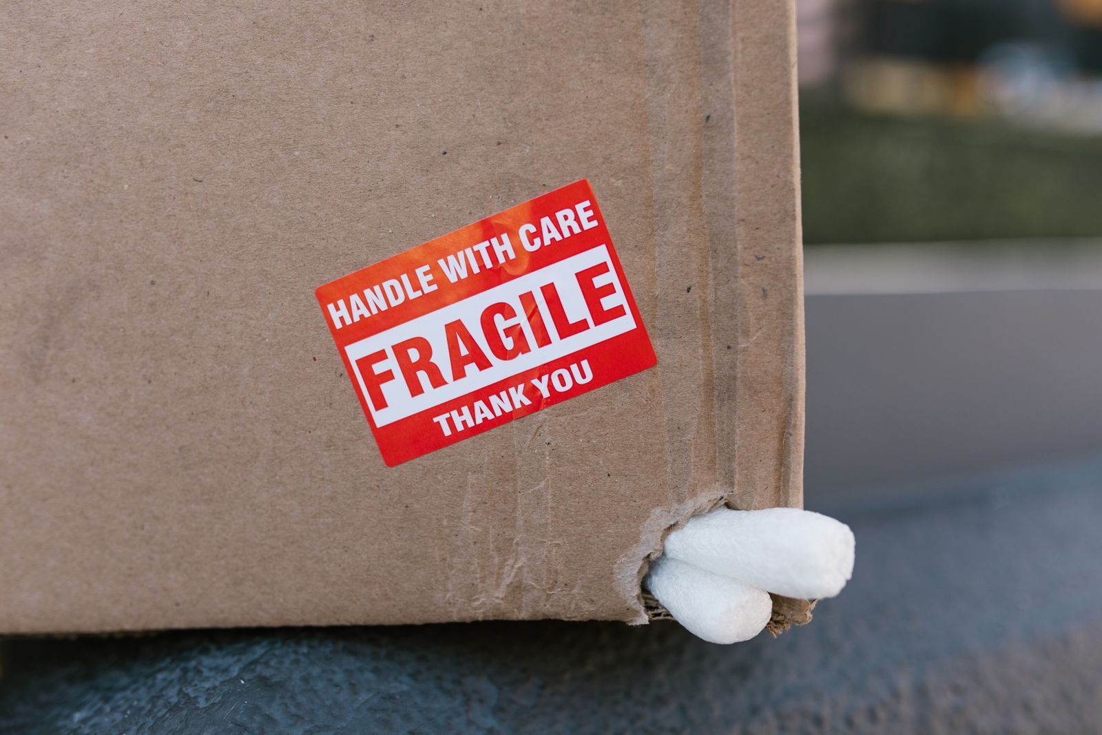 Close-up of a cardboard box with a 'fragile' sticker and packing peanuts visible.
